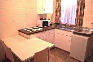 a small kitchen with a stove and a microwave at Barcelona Motel in Taupo