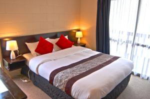 a bedroom with a large bed with red pillows at Barcelona Motel in Taupo
