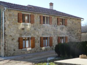 un antiguo edificio de piedra con ventanas de madera con contraventanas en Agroturism Stara Štala, en Borut