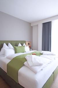 1 dormitorio con 1 cama grande con almohadas blancas en Mahorko Wein Wellness Wasserbüffel, en Glanz an der Weinstraße