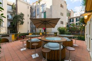 une terrasse avec des tables, des tabourets et un parasol dans l'établissement Spagna Ave, à Rome