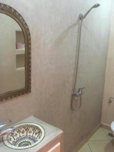 uma casa de banho com um lavatório e um chuveiro com um espelho. em Inna guest house em Mirleft