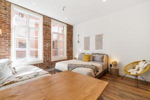 a bedroom with two beds and a brick wall at INITIAL - LOFT LAMA - Centre-Ville de Québec in Quebec City