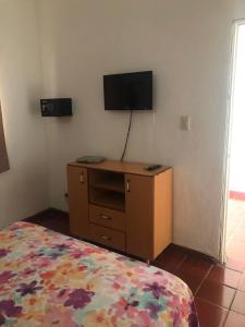 1 dormitorio con 1 cama y vestidor con TV en la pared en BocaChica Beach Hotel, en Boca Chica