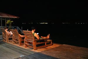 two people sitting in chairs by the water at night at Vista Mar Hotel  in Bocas Town