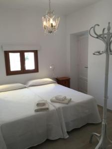 a white bedroom with a large white bed with two towels at Casa Can Joan Guasch in Sant Francesc Xavier