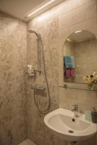 a bathroom with a shower and a sink and a mirror at Nidos Rojus in Nida