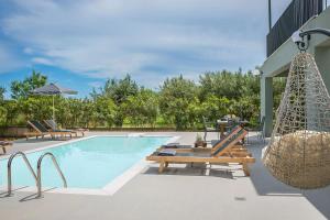 a swimming pool with chairs and a hammock next to a building at Villa Lantana in Skala Kefalonias