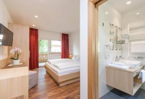a bedroom with a bed and a bathroom with a sink at Alpin Hotel Gudrun in Colle Isarco