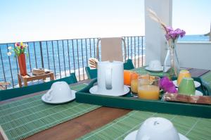 una mesa con una bandeja de comida y bebida en el balcón en Le Terrazze di Apollo - Case Tilotta, en Marinella di Selinunte
