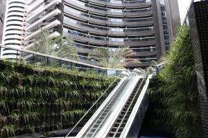 an escalator in front of a tall building with palm trees at Landscape Beira-Mar Perfect in Fortaleza