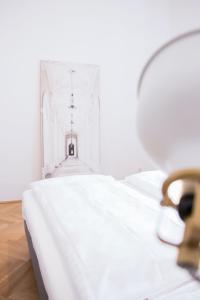 ein weißes Zimmer mit einem Bett und einem Spiegel in der Unterkunft HeyMi Apartments Stephansdom in Wien