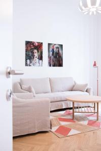 ウィーンにあるHeyMi Apartments Stephansdomの白いソファ付きのリビングルーム、壁に3枚の絵画