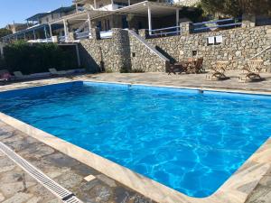 a large blue swimming pool in front of a building at Luxury White Maisonette in Kalafatis
