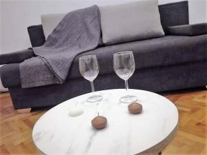 two wine glasses on a white table in front of a couch at Inspired by A.C. in Šibenik