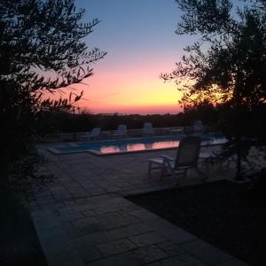 a chair sitting next to a swimming pool at sunset at Trulli Dal Conte in Locorotondo