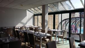 ein Esszimmer mit Tischen und Stühlen und Fenstern in der Unterkunft Hotel des Thermes et du Casino in Luc-sur-Mer