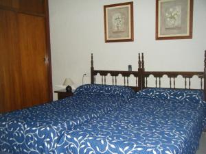 a bedroom with two beds with blue comforter at Hostal Muriel in Aljaraque