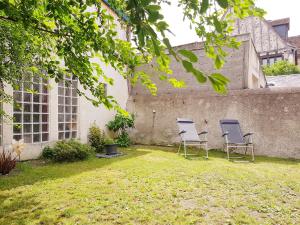 two chairs sitting in a yard next to a wall at La Parenthèse in Amboise