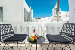 two chairs and a table with fruit on a balcony at Little Venice Villas in Mýkonos City