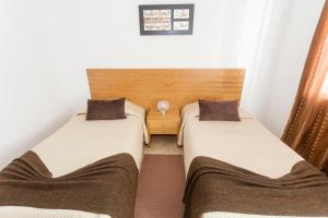 twee bedden in een kleine kamer met witte muren bij Apartamentos Oliveira in Madalena