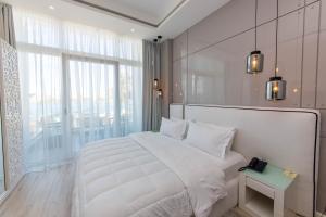 a white bedroom with a large bed and a window at Demi Hotel in Sarandë