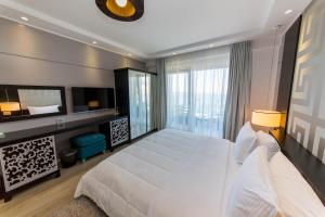 a bedroom with a large white bed and a large window at Demi Hotel in Sarandë