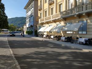 un bâtiment avec des tables et des parasols blancs dans une rue dans l'établissement Europalace Hotel, à Verbania