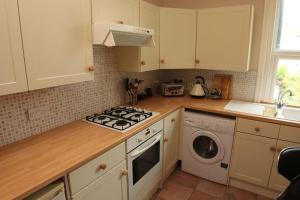 a kitchen with a stove and a washing machine at Evee's Pebbles 1 in Eastbourne