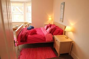 a bedroom with a bed with red sheets and a window at Evee's Pebbles 1 in Eastbourne