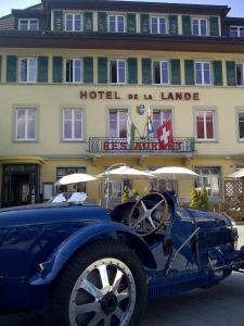 un viejo coche azul estacionado frente a un hotel en Hotel de la Lande en Le Brassus