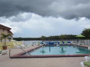 a swimming pool with chairs and a cloudy sky at River Wilderness Waterfront Cabins in Everglades City