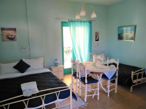 a bedroom with two beds and a table and chairs at Mouragio Apartments in Tyros