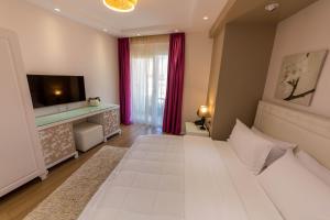 a bedroom with a large white bed and a television at Demi Hotel in Sarandë