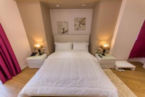 a bedroom with a large white bed with two night stands at Demi Hotel in Sarandë