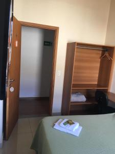 a room with a bed and a closet with a towel at Hotel Paulista in São José do Rio Pardo