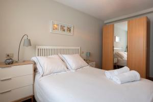 una camera da letto con un letto con lenzuola bianche e uno specchio di Apartamento Bed&Center 2A a Lugo