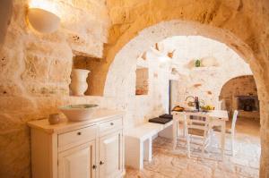 a kitchen with a table and a stone wall at Trulli Santa Maria dei Grani - Authentic Puglia Trulli with Private Pool & Scenic Garden in Ceglie Messapica