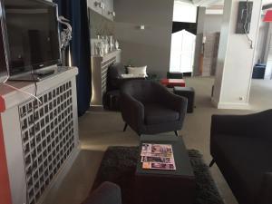 a living room with two chairs and a flat screen tv at Hotel des Thermes et du Casino in Luc-sur-Mer