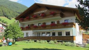 a large building with flowers on the balcony at Pension Tannenhof in San Giovanni in Val Aurina