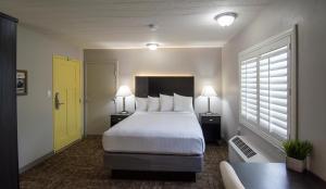 a hotel room with a bed and a yellow door at Americana Modern Hotel in Redding