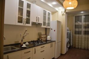 a kitchen with white cabinets and a sink and a refrigerator at Massiv Apt in Yerevan
