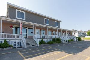 a building with white railings on a parking lot at Motel au Vieux Piloteux in Rivière-du-Loup