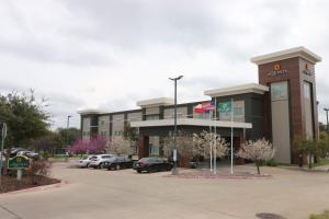 un immeuble de bureaux avec des voitures garées dans un parking dans l'établissement La Quinta by Wyndham Austin NW/Lakeline Mall, à Cedar Park