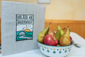 a bowl of apples and pears next to a book at Bauernhof Katin in Tröpolach