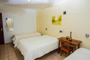 a bedroom with two beds and a table with a desk at Santa Maria Hotel in Cascavel