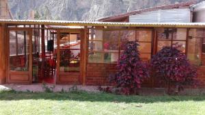Hostal Pachar في أولانتايتامبو: مبنى بأبواب زجاجية ونباتات ارجوانية