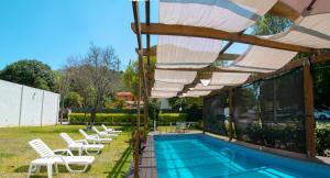 a swimming pool with white chairs and an umbrella at Relax Inn Suites in San Andrés Tuxtla