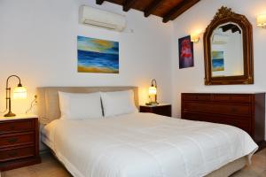 a bedroom with a large white bed and a mirror at Orestis Suites in Kolios