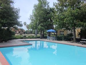 a blue swimming pool with a table and an umbrella at Sonesta Simply Suites Stafford in Stafford